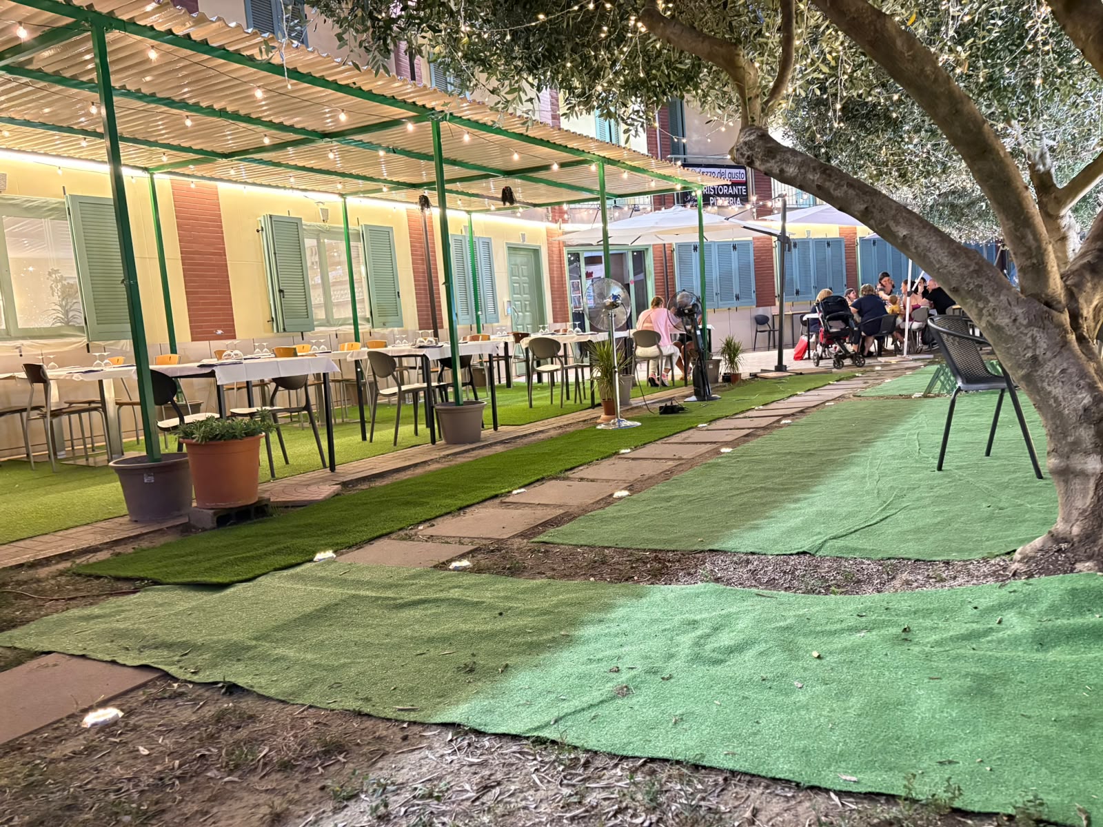 Dehor esterno del ristorante pizzeria, di giorno, con tavoli e insegna