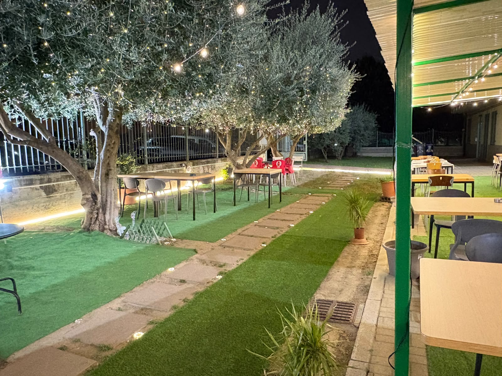 Giardino esterno de Il Palazzo del Gusto con ulivi illuminati la sera