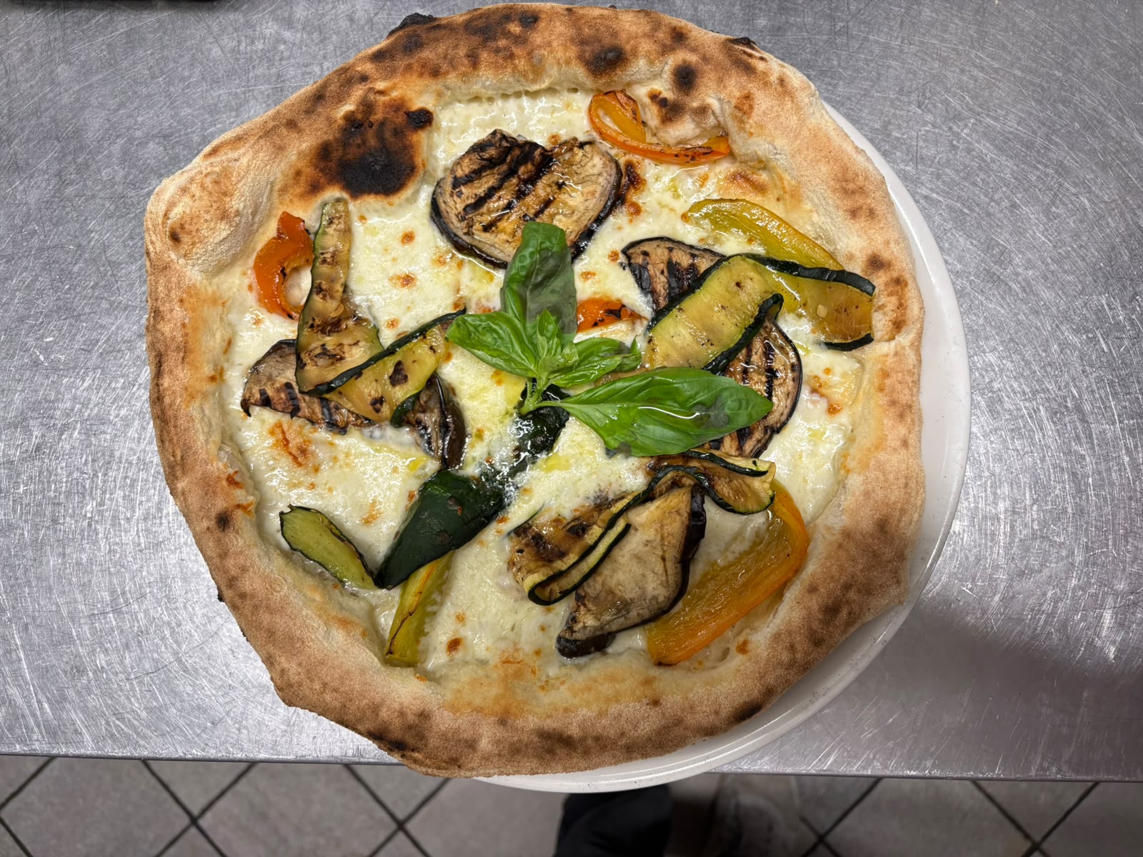 Pizza gourmet con verdure grigliate, mozzarella filante e basilico fresco